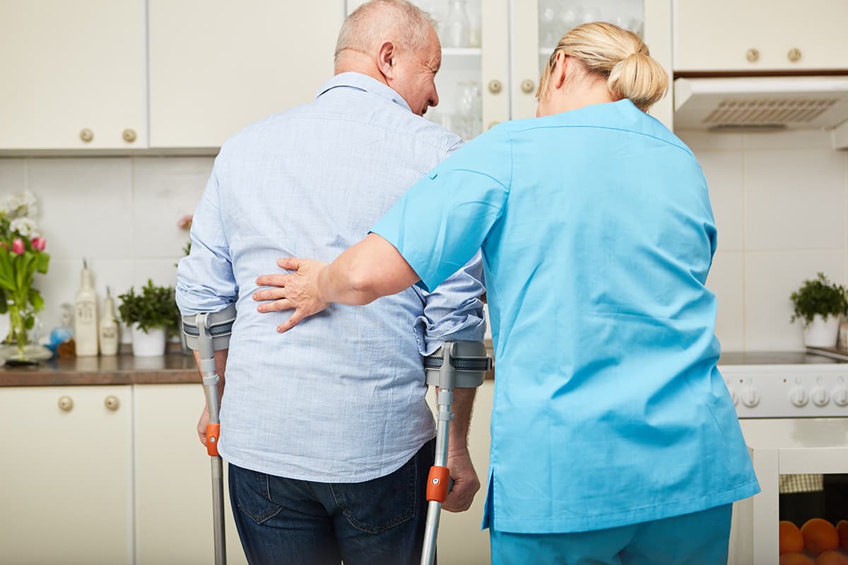 Aide helping a patient walk with arm braces