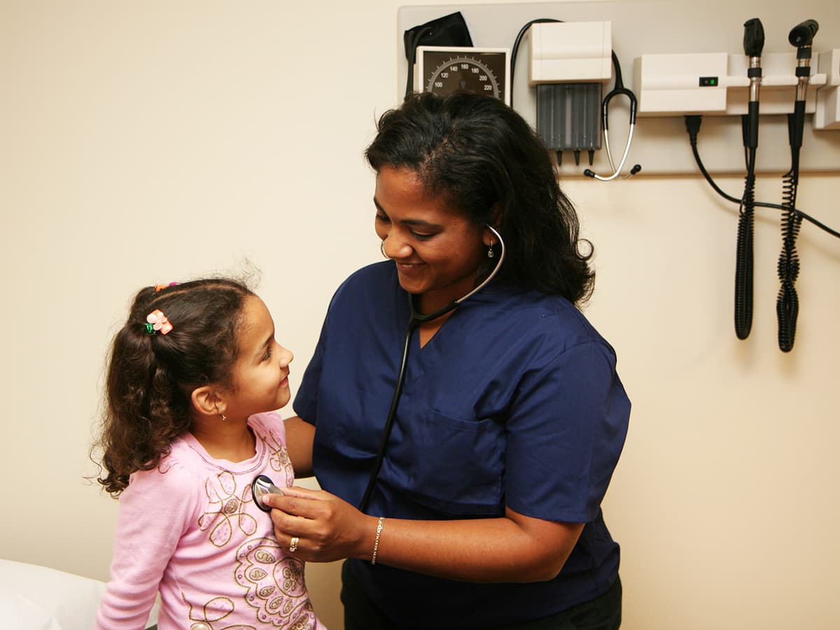 Medical assistant checking a child patient's heartbeat.