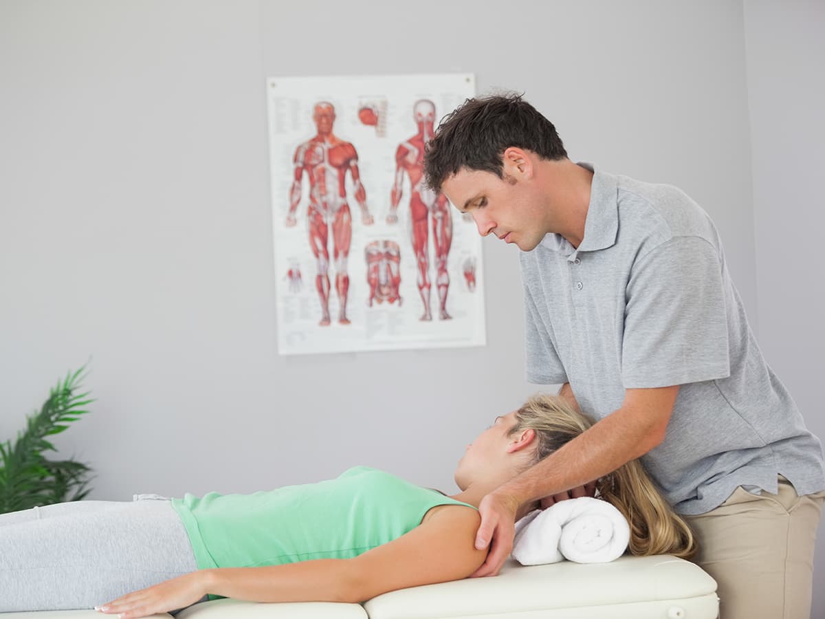 A natural health specialist working with a patient lying down