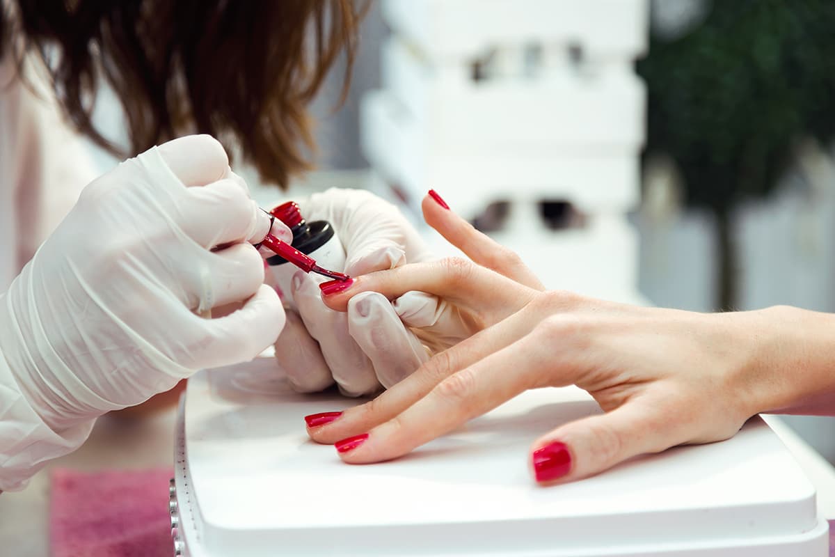 woman getting nails painted red